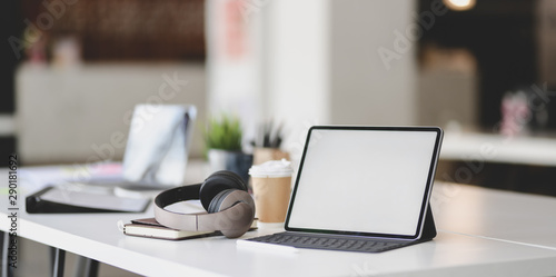 Blank screen tablet with on-ear headphones and office supplies on white table