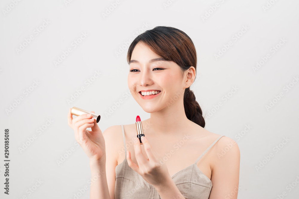 Photo of a beautiful young pretty asian woman with healthy skin posing naked isolated over white wall background holding lipstick. Photo of a beautiful young pretty asian woman with healthy skin posing naked isolated over white wall background holding lipstick.