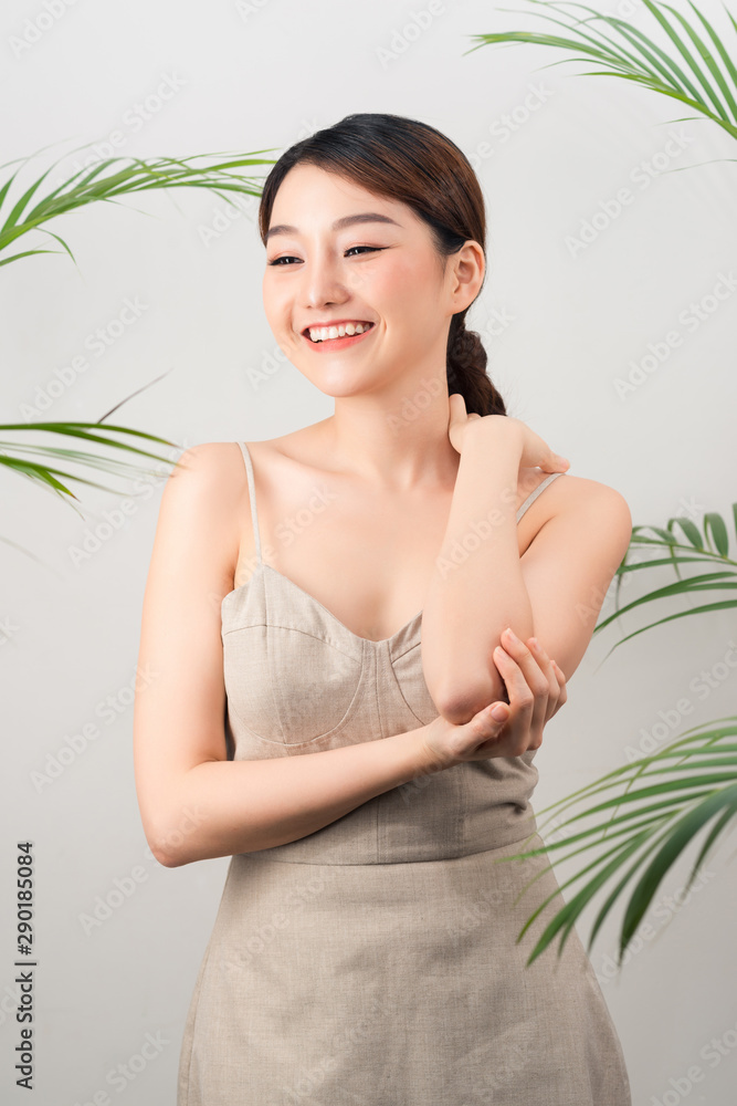 Portrait of Asian happy woman standing with green leaves around her on white background Portrait of Asian happy woman standing with green leaves around her on white background