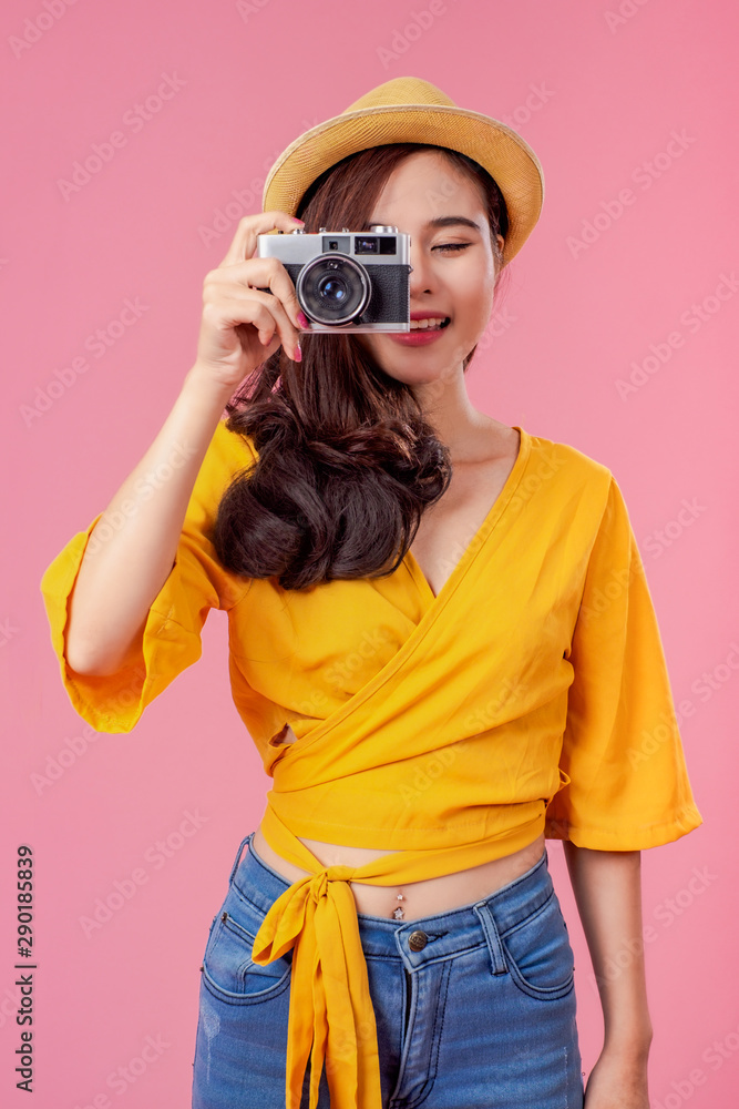 Smiling woman traveler holding camera in holiday on pink backgrounds, relaxation concept, travel concept Smiling woman traveler holding camera in holiday on pink backgrounds, relaxation concept, travel concept