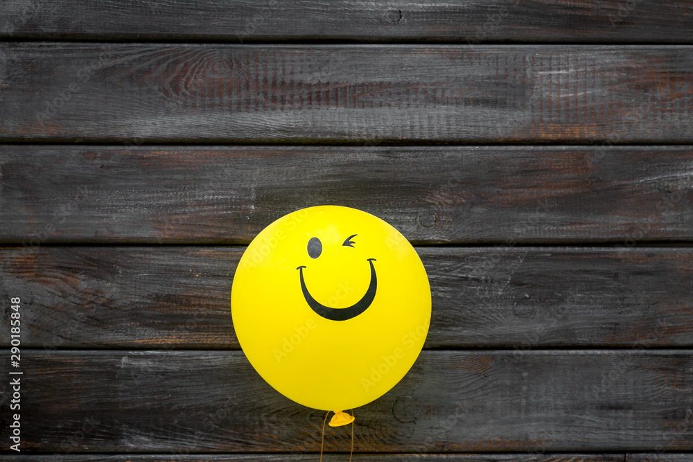 Naklejka Happiness emotion. Yellow balloon with smile on dark wooden background top view space for text