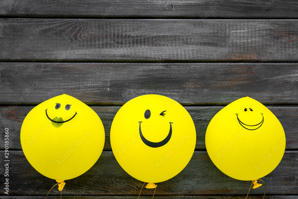 Naklejka Happiness emotion. Yellow balloon with smile on dark wooden background top view space for text