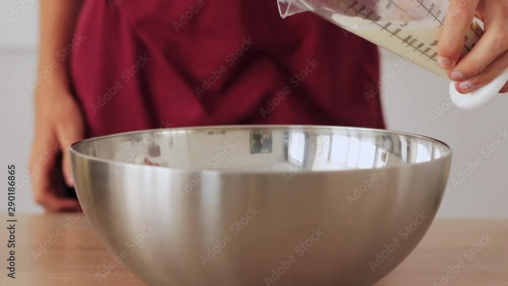 Milk being poured into a metal bowl for a batter / 40% Slowmotion Milk being poured into a metal bowl for a batter / 40% Slowmotion