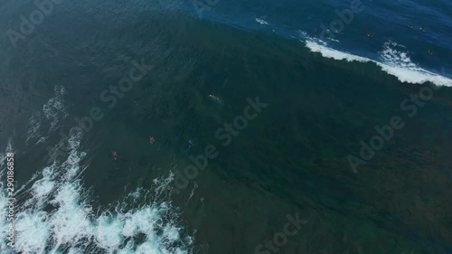 A Surfer riding a wave while others wait in line on the Caribbean island of Tobago photo