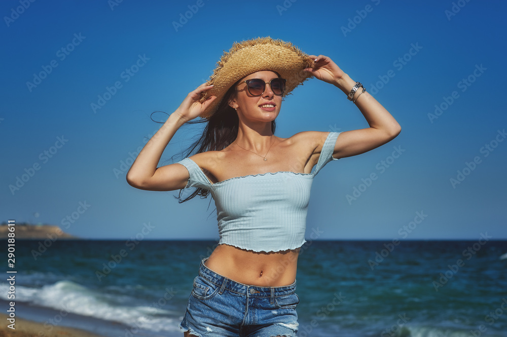 Young happy woman walking on the beach by the sea .Girl in shorts and blouse