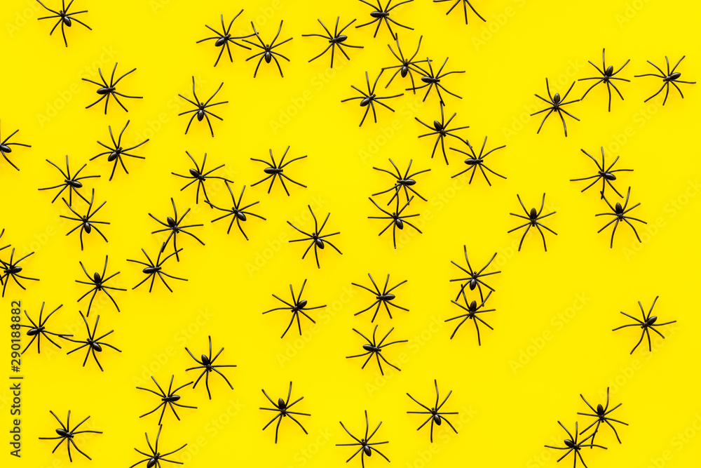 Minimalistic Halloween background with small spiders on yellow table top view Minimalistic Halloween background with small spiders on yellow table top view