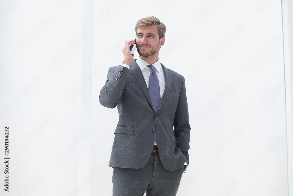 businessman talking on a mobile phone standing near the office window businessman talking on a mobile phone standing near the office window