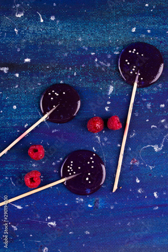 Colourful lollipop with raspberry on the blue background