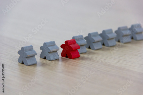 Gray gaming pieces and a red meeple, diversity concept