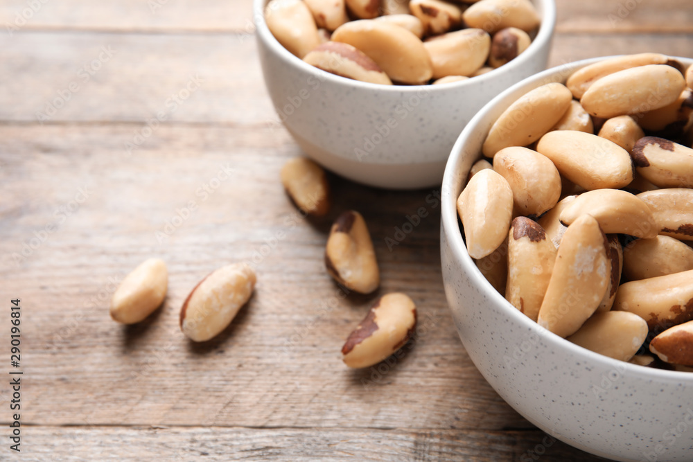 Bowls with tasty Brazil nuts on wooden table. Space for text Bowls with tasty Brazil nuts on wooden table. Space for text