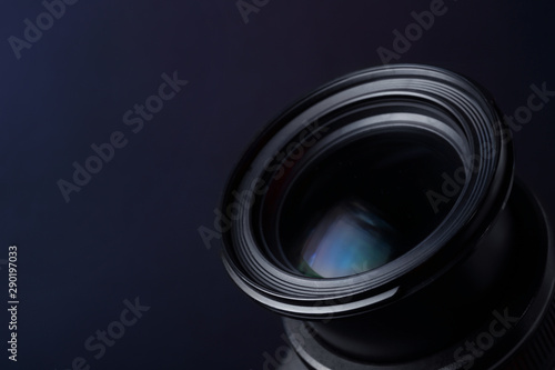 Lens of professional camera on dark blue background, closeup. Space for text