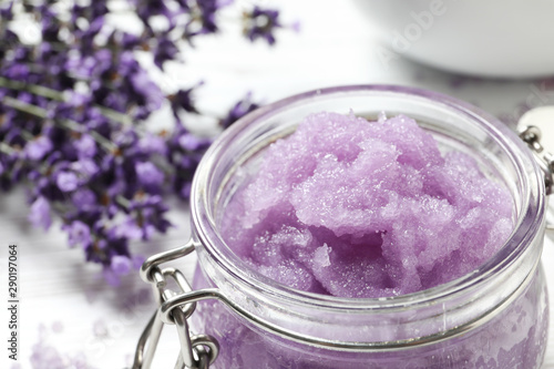 Slika na platnu Glass jar of natural sugar scrub and lavender flowers on table, closeup with space for text