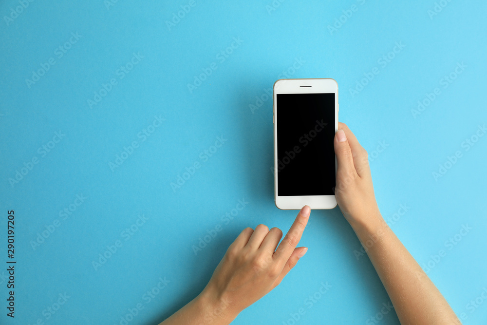 Woman holding modern phone on blue background, top view. Space for text - obrazy, fototapety, plakaty 