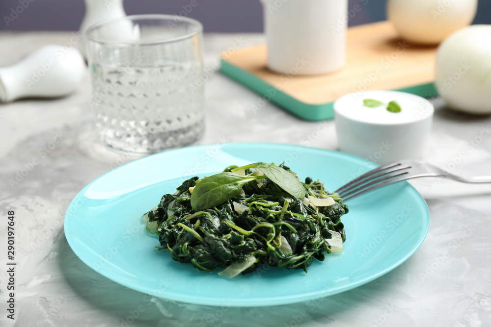 Tasty cooked spinach and fork on grey table. Healthy food Tasty cooked spinach and fork on grey table. Healthy food