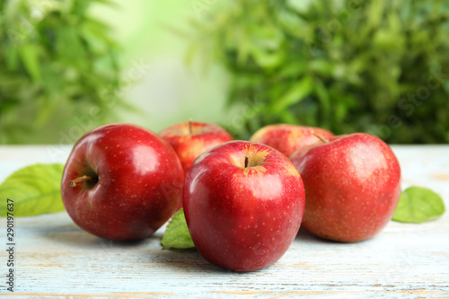 Ripe juicy red apples on white wooden table against blurred background. Space for text