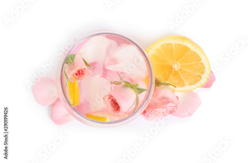 Tasty refreshing lemon drink with roses on white background, top view