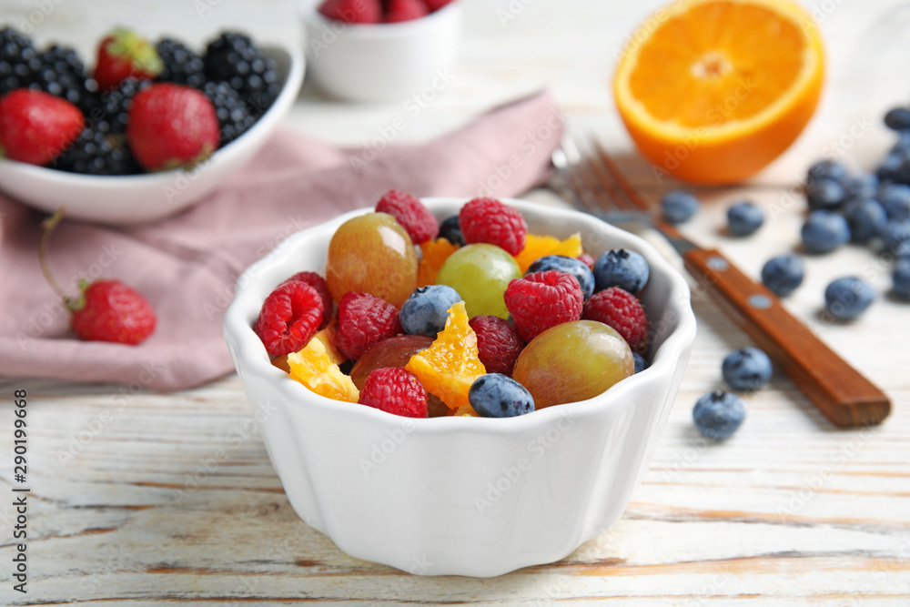 Fresh tasty fruit salad on white wooden table