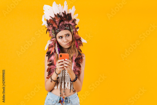 Woman in carnival suit isolated over yellow wall using mobile phone.