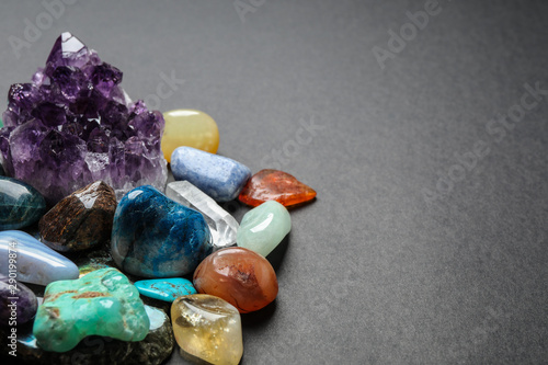 Different gemstones on dark table, space for text