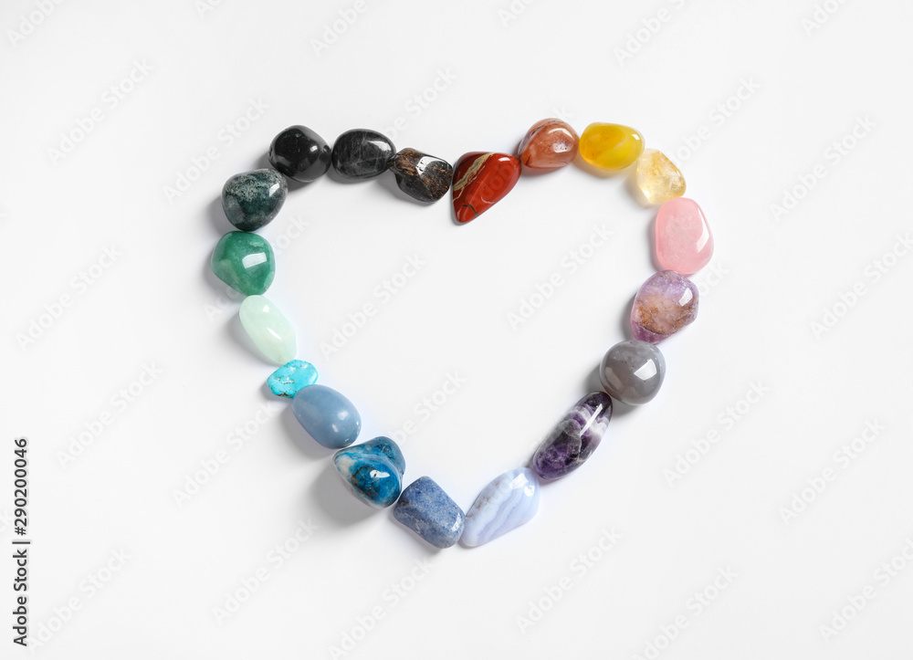 Heart shaped frame made with different beautiful gemstones on white background, top view. Space for text Heart shaped frame made with different beautiful gemstones on white background, top view. Space for text