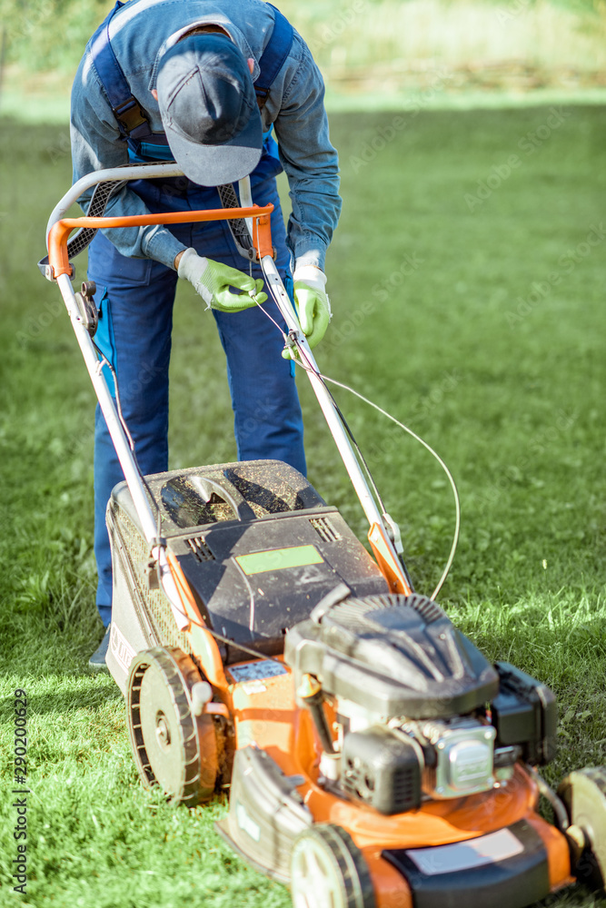 Professional gardener repairing gasoline lawn mower while cutting grass on thhe backyard Professional gardener repairing gasoline lawn mower while cutting grass on thhe backyard