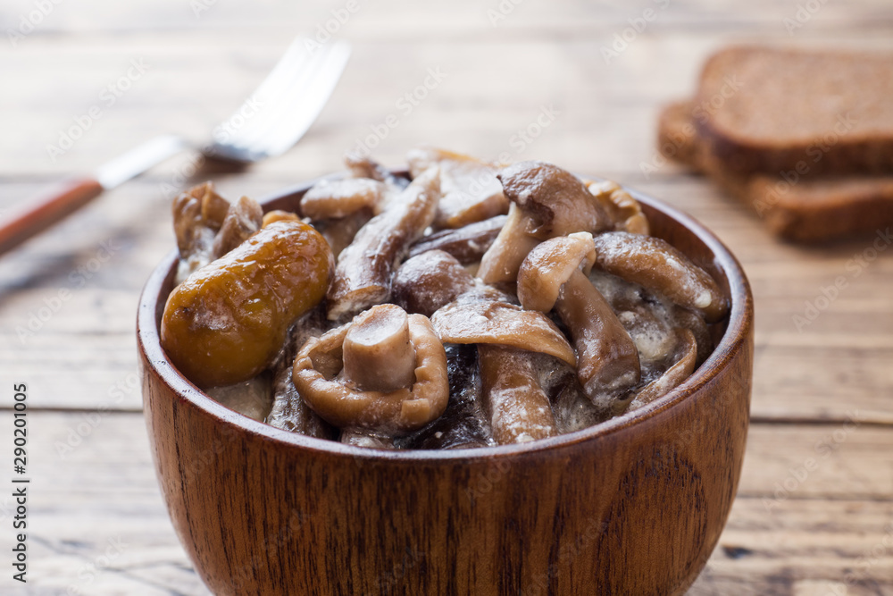 Stewed mushrooms in a sauce with sour cream and cheese in a wooden bowl. Stewed mushrooms in a sauce with sour cream and cheese in a wooden bowl.