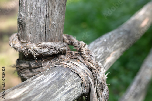 knot of old rope tied on a wooden base of the fence © Olya