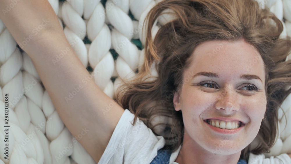 Fototapeta premium A young girl lies on a merino white blanket in the park and enjoys the summer weather.