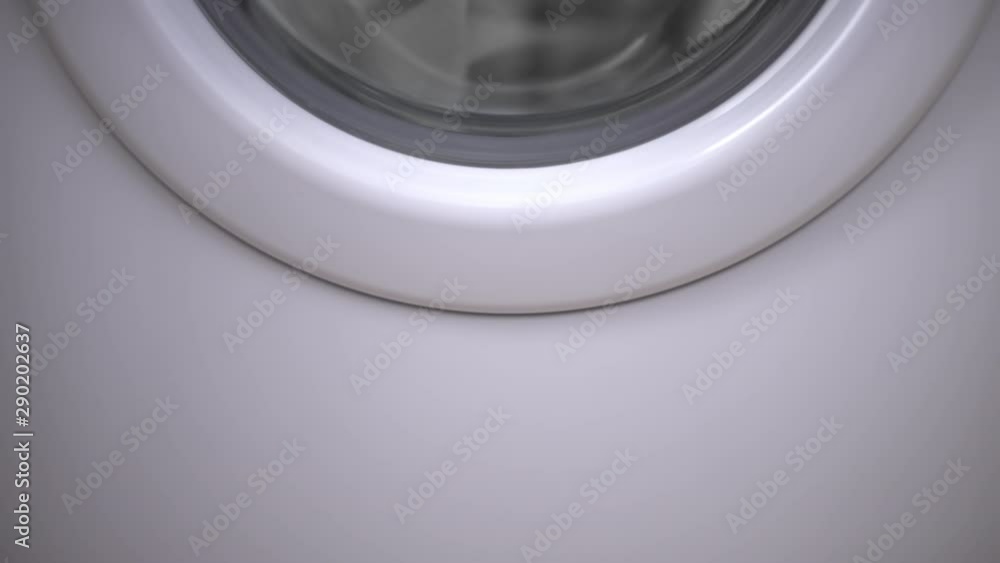 Half of the door of a white washing machine during the spin- drying. Half of the door of a white washing machine during the spin- drying.