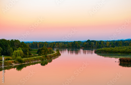Scenic view of the Lower Inn river at sunset  in early autumn with swans swimming in the background. © Jesus