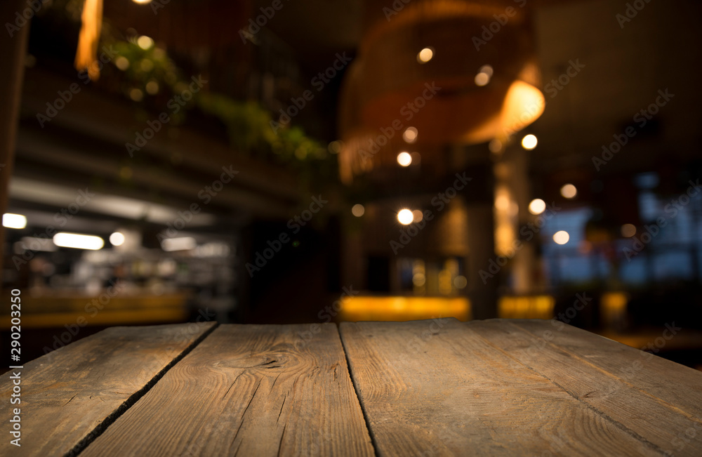 Empty wood table top on blur light gold bokeh of cafe restaurant in dark background