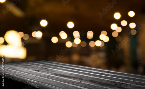 Empty wood table top on blur light gold bokeh of cafe restaurant in dark background