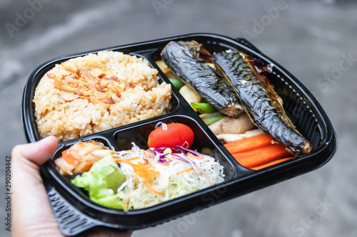 Take away a bento box of grilled Saba fish, grilled vegetables, salad, garlic fried rice and kimchi on hand; easy meal with healthy food.