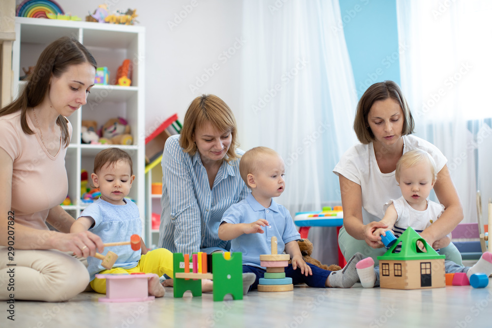 Fototapeta premium Śliczne maluszki z rodzicami bawiące się w przedszkolu