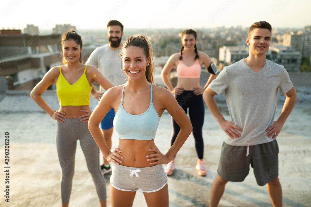 Fototapeta premium Group of young happy people friends exercising outdoors at sunset.