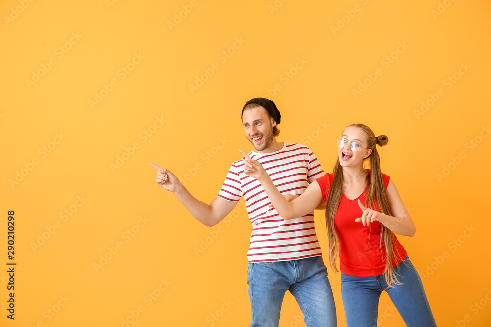Fototapeta premium Cool young couple dancing against color background