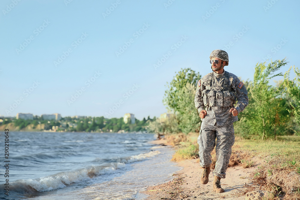 Running soldier in camouflage near river