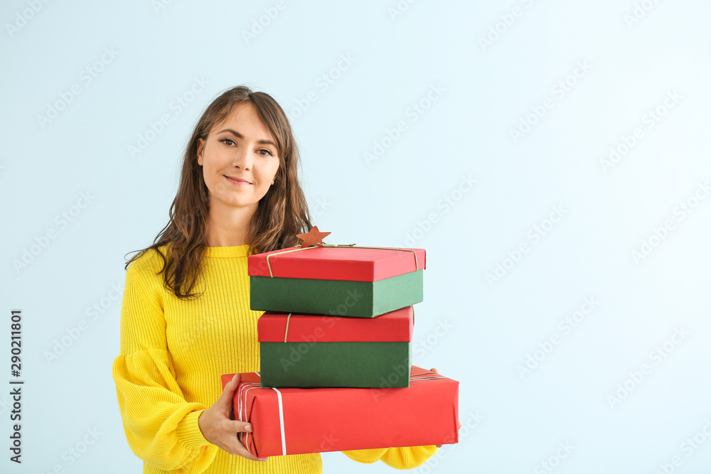 Happy young woman with Christmas gifts on light background Happy young woman with Christmas gifts on light background