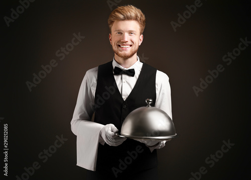 Handsome waiter with tray a...