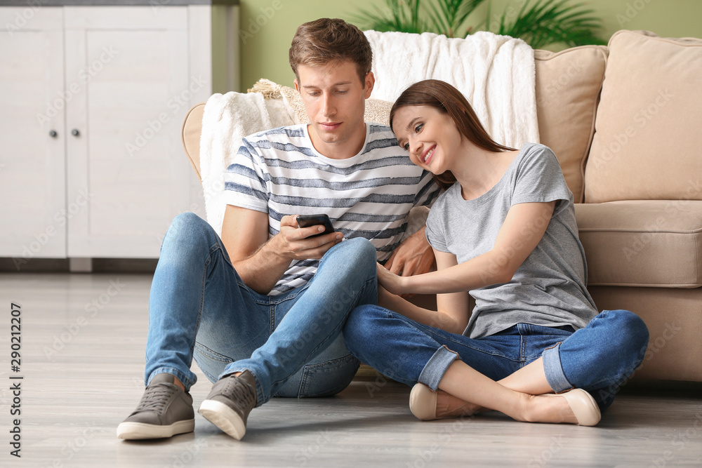 Young couple with mobile phones relaxing at home