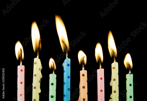 Burning colorful birthday candles on black background