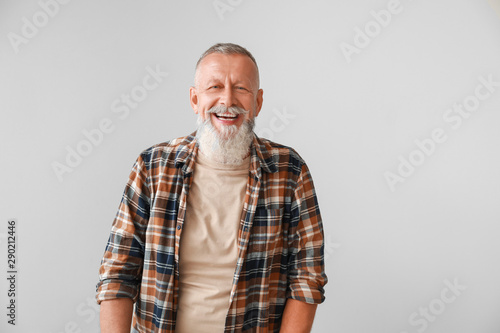 Happy mature man on grey ba...