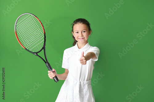 Little girl with tennis racket showing thumb-up on color background