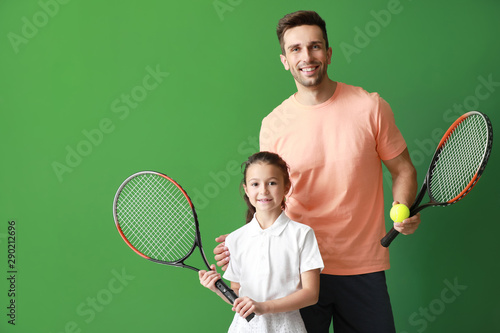 Little girl and her father with tennis rackets on color background © Pixel-Shot