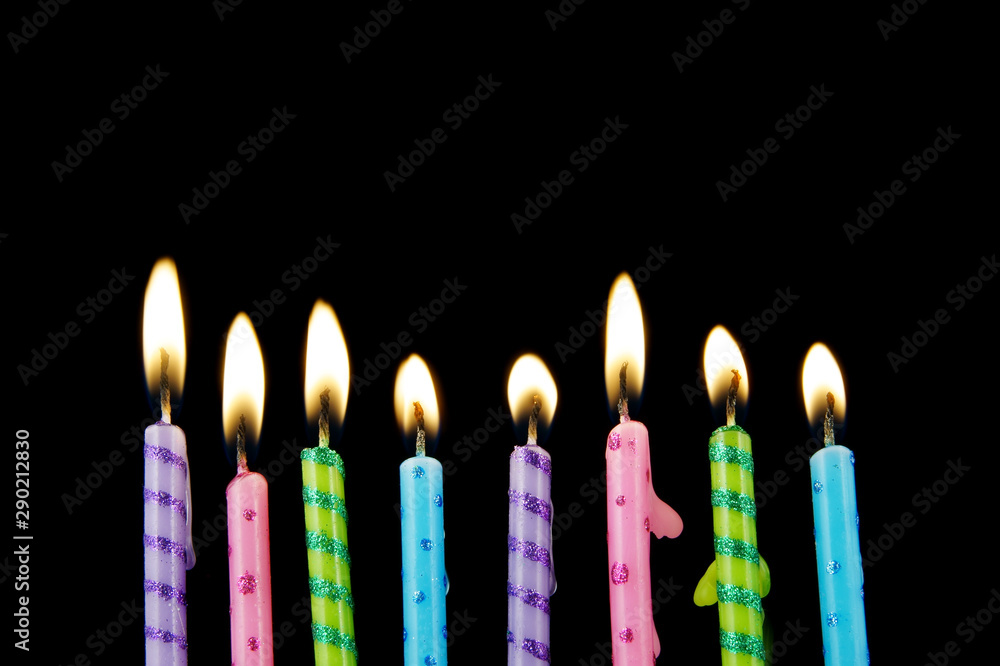 Colorful burning birthday candles on black background Colorful burning birthday candles on black background