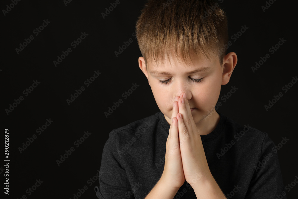 Praying little boy on dark background Praying little boy on dark background