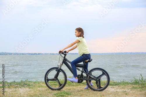Little girl riding bicycle near river