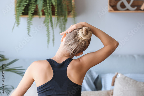 Young woman training at home, back view