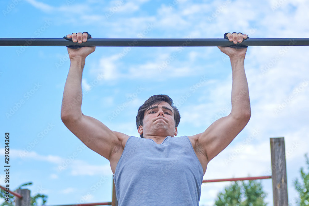 a sporty boy doing chin-ups, bottom view a sporty boy doing chin-ups, bottom view