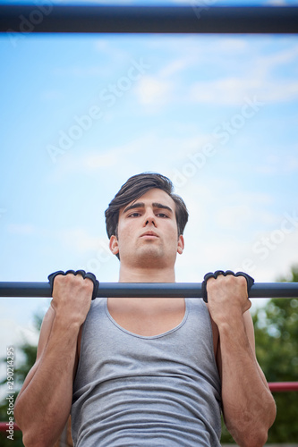a sporty boy doing chin-ups, bottom view, close up and vertical view
